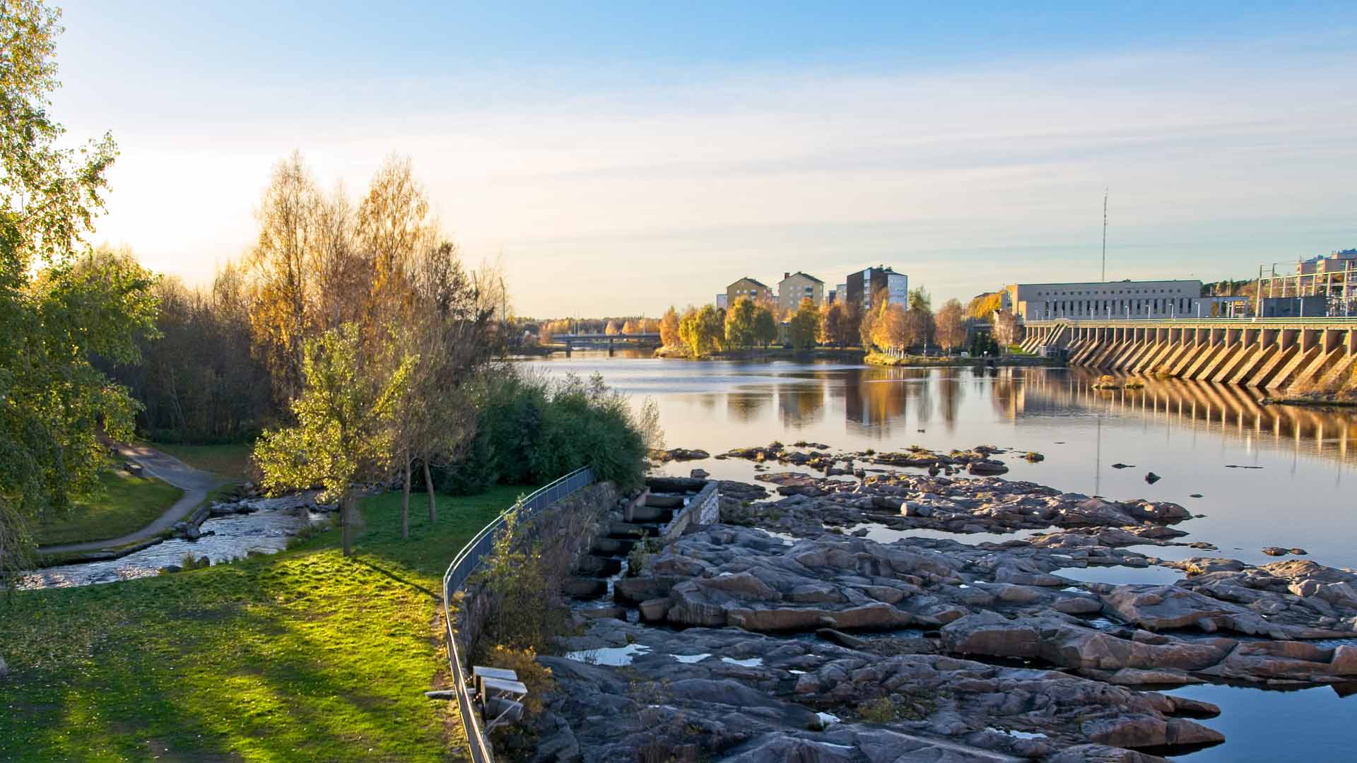 Kuvituskuva Oulusta, jossa näkyy puistoa, joki sekä kaupunkinäkymää.