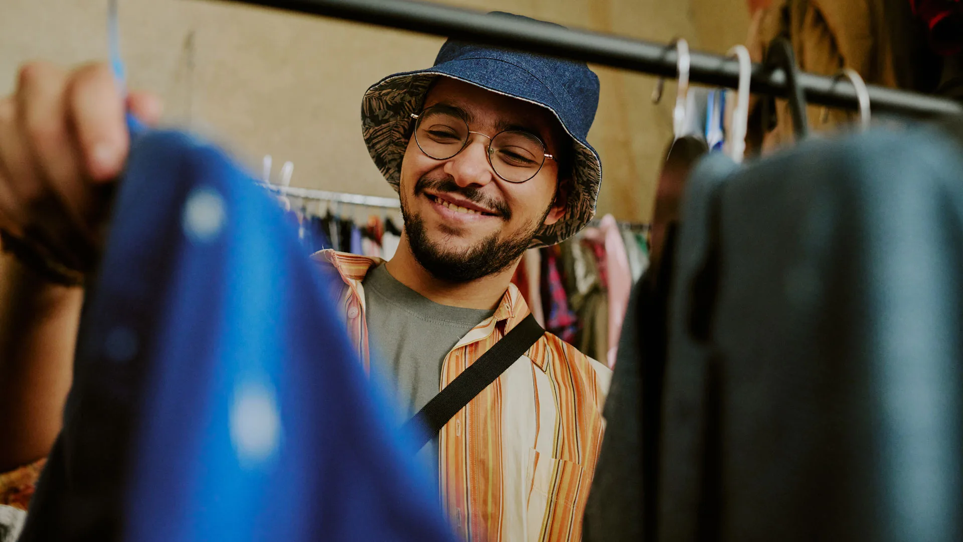 Hymyilevä nuori mies vaateostoksilla.