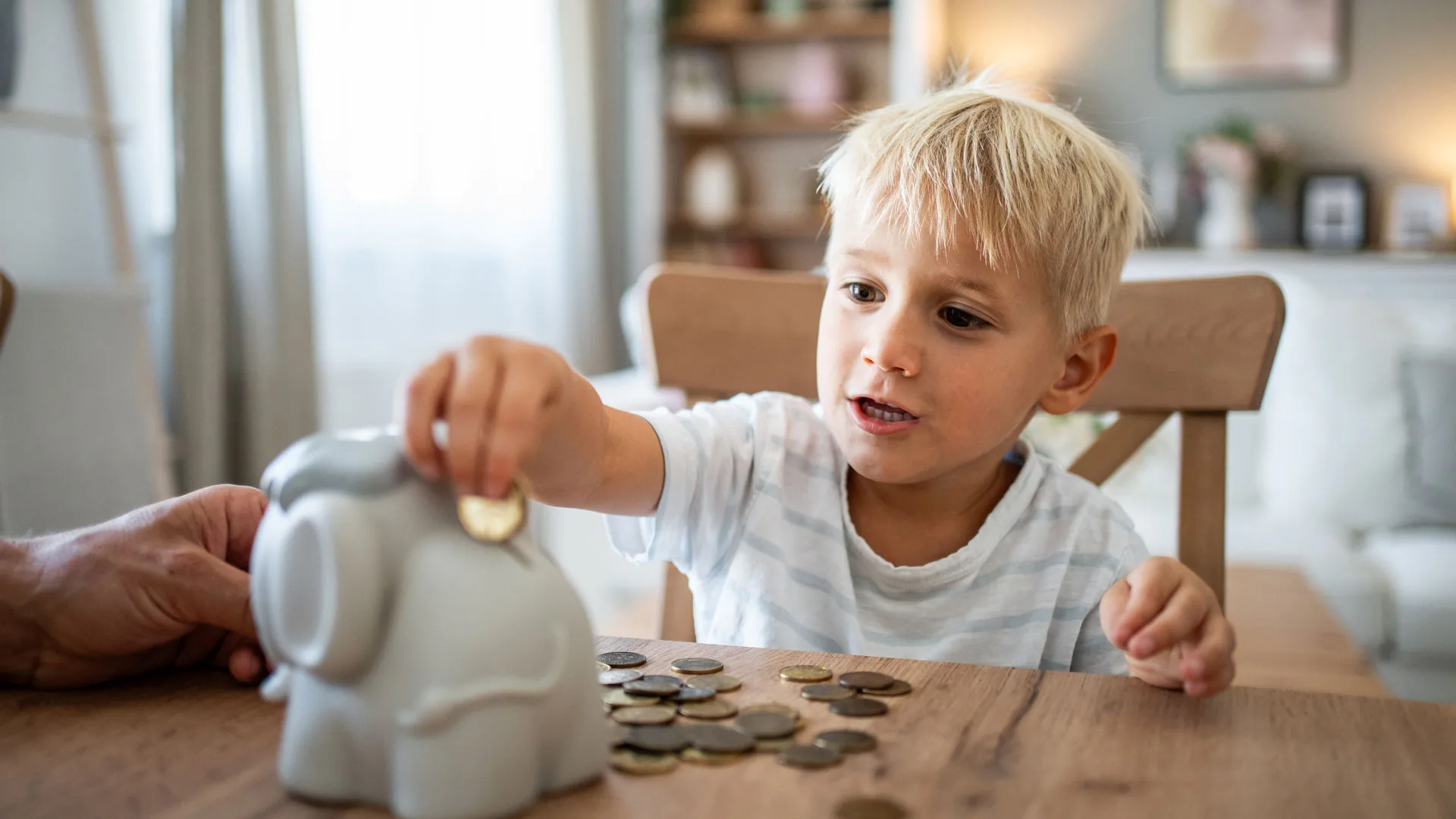Pieni poika laittamassa kolikkoa säästöpossuun.